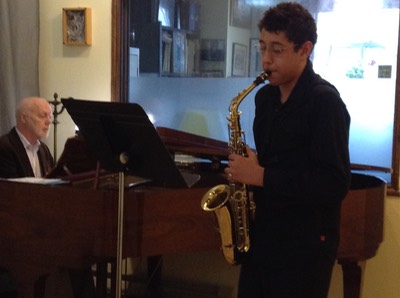 Jean-Pierre Schmitt accompanies young student playing saxophone.